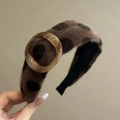 Dettaglio di un cerchietto in peluche marrone a pois con fibbia in resina effetto marmo - Caffè Scuro