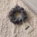 Détail d'un chouchou en tissu à carreaux noir et blanc avec une étiquette de marque - Élastique à Carreaux Noir