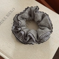 Detailed view of gray knitted scrunchie with striped trim on textured fabric book - Light Gray