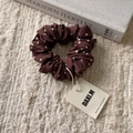 Close-up of brown polka dot scrunchie with lace edge and branded DAXI.M tag on knit fabric - Polka Dot Hair Tie