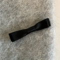 Close-up detail of a minimalist black bow hair clip made of ribbed ribbon fabric - Solid Color
