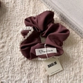 Close-up of burgundy fabric scrunchie with delicate white lace trim and handmade cloth label - Coffee