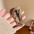 Detail of a brown houndstooth fabric triangular hair clip with a sturdy metal BB base - Triangle Style