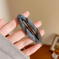 Close-up of oval hair clip with blue and brown woven fabric and black metal BB clip - Oval