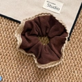 Deep coffee knit scrunchie with beige ruffled edges on rustic woven background - Coffee Crochet Edge Scrunchie