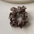 Vue détaillée du chouchou à carreaux café avec tissu fin en coton et étiquette de logo noire - Damier Café