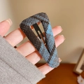 Close-up of a blue and brown plaid fabric covered triangle BB hair clip held in hand - Triangle Style