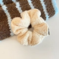 Nahaufnahme eines cremefarbenen Strick-Haargummis aus flauschigem Mohair mit kleinem Etikett - Milchaprikose