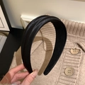 Detailansicht eines dicken schwarzen Satin-Haarreifs mit glatter, glänzender Textur - Schwarz