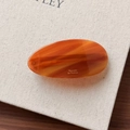 Detailed macro view of an oval amber texture barrette with Barrette la France gold lettering - Caramel color