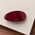 Close-up of a red oval marble resin hair clip with golden Barrette La France text engraving - Red