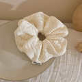 Detail of soft white knitted scrunchie with scalloped edges and minimalist brand label - White