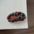 Close-up of handmade crochet Christmas hair clip with red and green knit patterns - Christmas Gold Bead Red Base
