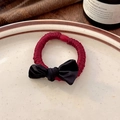 Close-up of red fabric hair scrunchie with a black satin bow on a ceramic plate - Black Bow Red Hair Tie