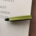 Macro shot of bicolored avocado green and black acetate banana hair clip on fabric - Green
