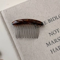 Dettaglio del pettine per capelli tartarugato con denti in metallo e scritta dorata - Sfumatura blu marrone