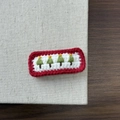 Detail of handcrafted knitted Christmas tree hair clip with festive red and green colors - Christmas Tree Red Edge