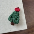 Close-up of handmade knit Christmas tree hair clip with green yarn and pearl accents - Christmas Apple Tree