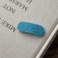 Detailed macro view of a turquoise marble acetate hair clip on a vintage fabric book cover - Textured Blue