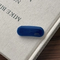 Close-up of deep blue oval acetate hair clip with FANRCE Handmade logo on a book - Dark Blue