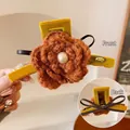 Detalle de pinza de pelo de flor con perla blanca y lazo de cuero para mujer - Naranja