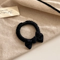 Close-up of a black satin bow scrunchie on a rustic beige linen background with card - Black