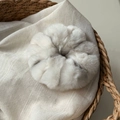 Detalle macro de un coletero de piel sintética suave y esponjosa en una cesta tejida - Blanco