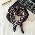 Elegante pañuelo de seda con estampado de leopardo y borde negro en un escritorio - Leopardo Café Claro