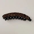 Close-up of leopard print fabric texture and plastic teeth on a banana hair clip - Coffee Leopard