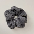 Detailed view of the vertical ribbed texture and white woven label on a grey knitted scrunchie - Grey Scrunchie