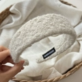Primer plano detallado de la diadema de lana rizada blanco crema con etiqueta hecha a mano - Blanco Roto