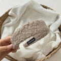 Detalle de diadema de sherpa beige con etiqueta textil negra hecha a mano de cerca - Caqui