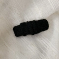 Close-up of black knitted hair clip with soft mohair texture on a beige linen fabric - Black