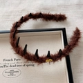 Detail view of brown plush headband with black anti-slip teeth and a gold metal label - Headband / Brown