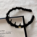 Detailed macro view of black faux fur headband with gold metal tag and punk spikes - Headband / Black