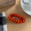 Barrette en tricot orange vif avec maille texturée sur un fond minimaliste en bois clair - Orange