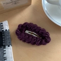 Détail d'une pince à cheveux tricotée violet foncé avec texture torsadée sur bois rustique - Violet