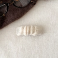 Gros plan sur une pince à cheveux en tricot crème avec texture ondulée pour l'automne - Blanc Cassé