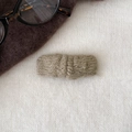 Gros plan sur une pince à cheveux en tricot vert haricot avec texture torsadée - Café Clair