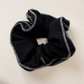 Detail of a handmade black knitted scrunchie with soft grey plush edges and label - Black Double-sided Style