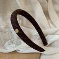 Dark coffee diagonal striped headband with gold metal logo on a soft linen background - Brown Stripes