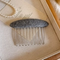 Detailed macro view of the dark grey wool texture and smooth metal teeth of the hair comb - Gray