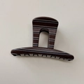 Detail einer dunkelbraun gestreiften Haarklammer mit glänzendem Harzfinish und weißen Zähnen - Braun Kurzline-Stil