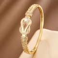 Goldener Hufeisen-Knoten-Armreif mit Zirkonia-Mikropflaster auf Seidenhintergrund - Gold