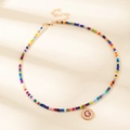 Collier de perles colorées avec un pendentif rond doré orné d'une lettre G de couleur violette - Lettre G