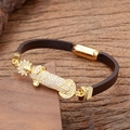 Vue macro d'un bracelet en cuir tressé marron avec pendentif religieux doré et zircons - Style Notre-Dame de Guadalupe
