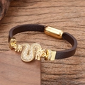 Pulsera de cuero para hombre con amuleto de dragón dorado y cristales en fondo de madera - Estilo Dragón