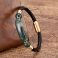 Detail eines schwarzen geflochtenen Lederarmbands mit grünen Steinperlen und Goldverschluss - Gold-Grüner Stein
