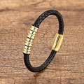 Geflochtenes Lederarmband in Schwarz mit goldenen Ringen auf Holzoberfläche - Gold