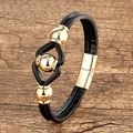 Close-up of black braided leather bracelet with three polished gold steel beads on wood - Gold